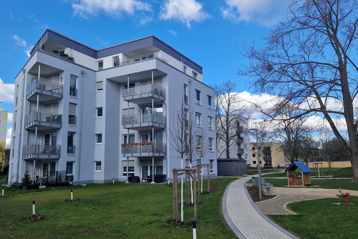 Modernes Wohnhaus mit blauer Fassade und umliegender Grünfläche.
