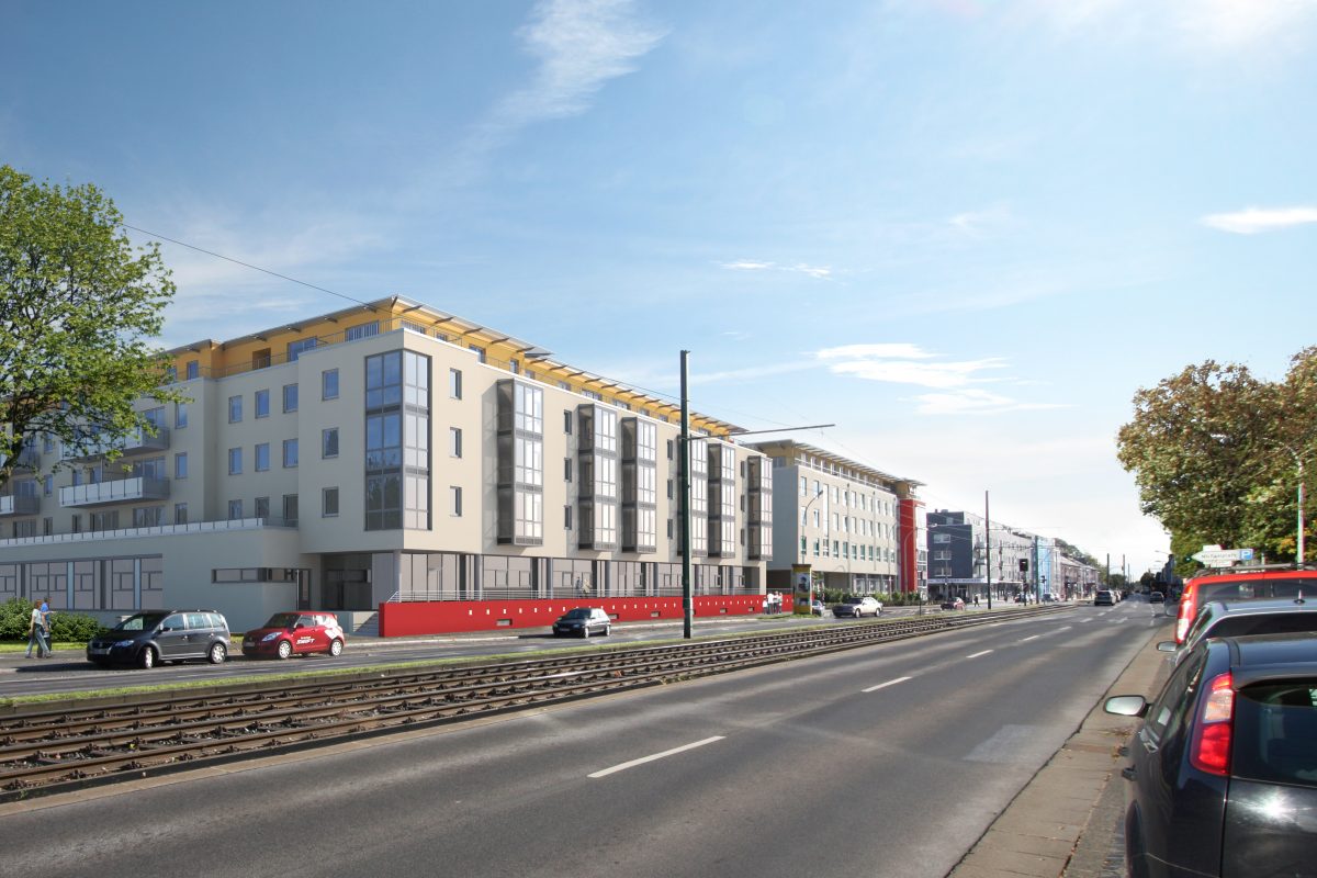 Straßenzug mit modernem Pflegeheim entlang von Gleisen.