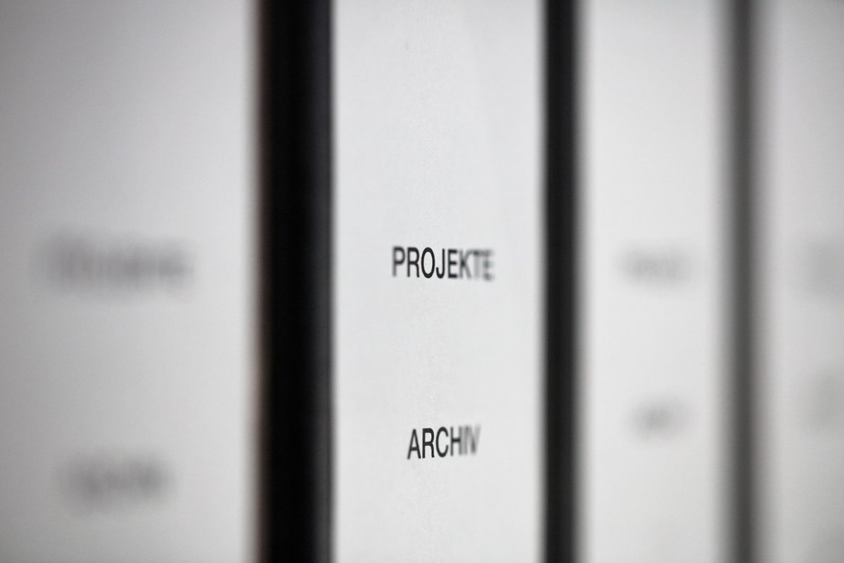 Nahaufnahme von beschrifteten Ordnern mit „PROJEKTE“ und „ARCHIV“.