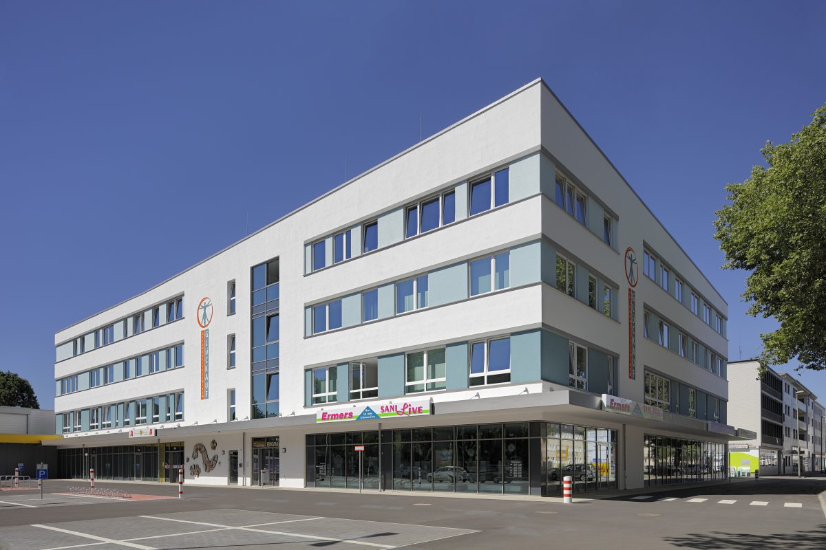 Eckansicht eines modernen Ärztehauses mit Geschäften im Erdgeschoss.