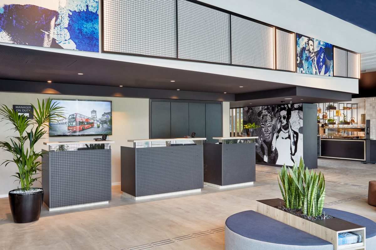 Stylischer Hotellobby-Empfang mit Kunstwand, TV und modernen Tresen.
