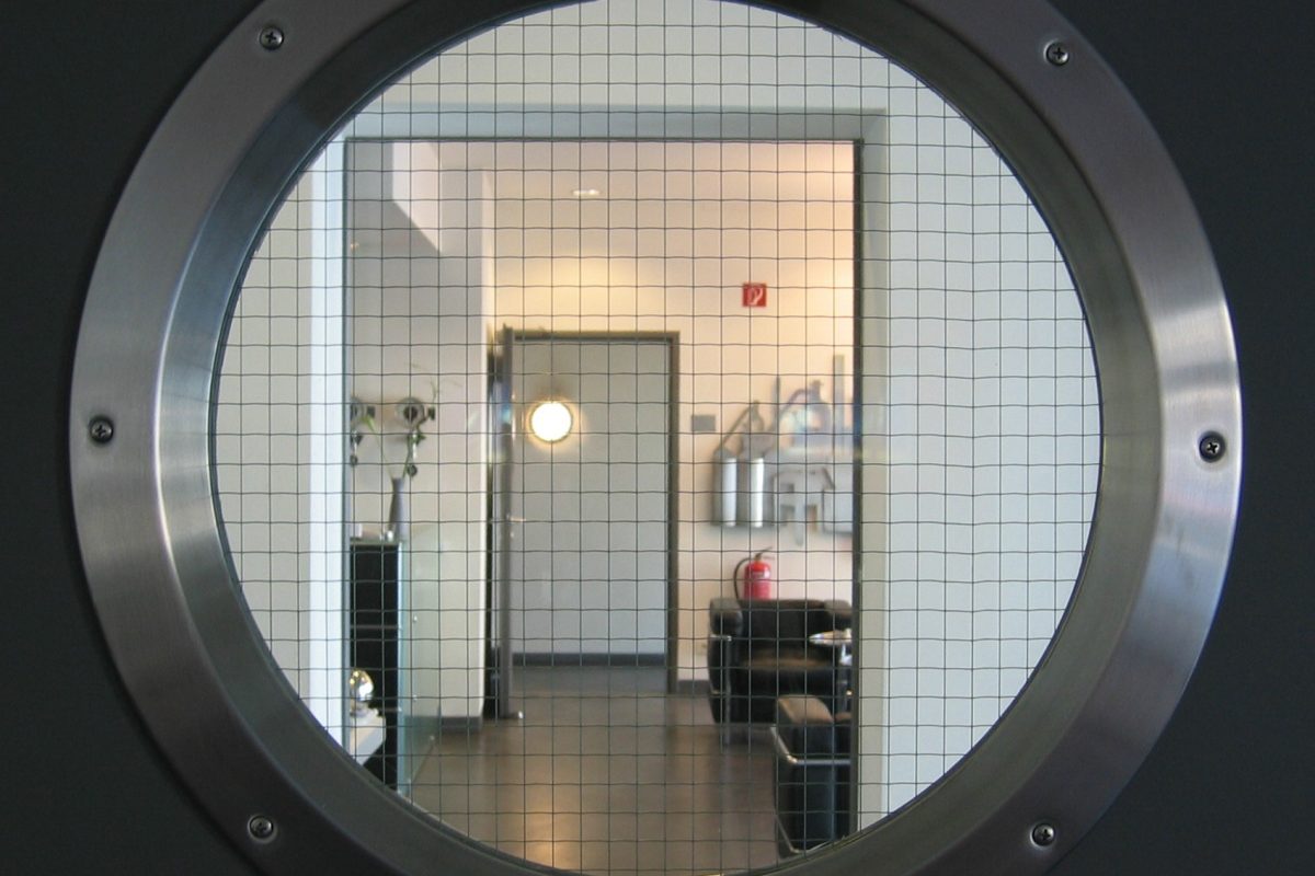 Blick durch rundes Bullauge in Foyer mit zeitlosen Möbelklassikern.