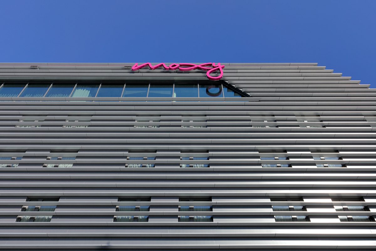 Moxy-Schriftzug auf moderner Lamellenfassade mit Fensterreihen