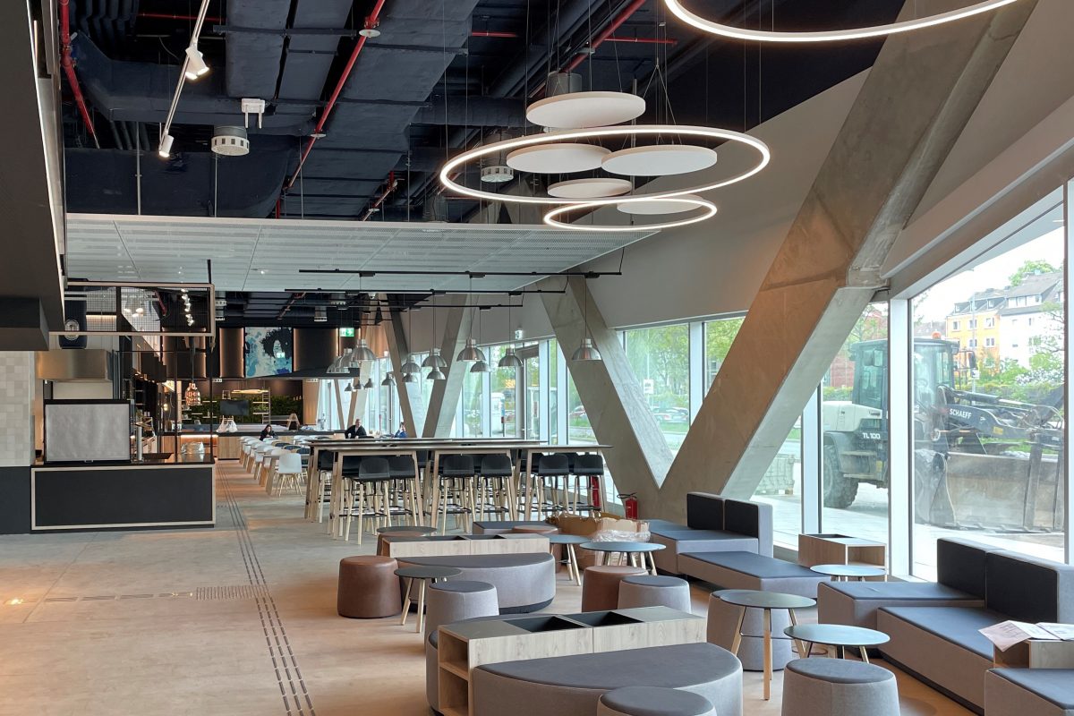 Großzügiges Hotelrestaurant mit hohen Tischen, Lounge-Möbeln und großen Fenstern.