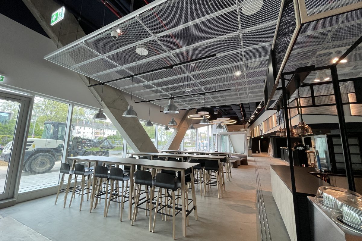 Modernes Hotelrestaurant mit hohen Tischen, Barhockern und großflächigen Fenstern.