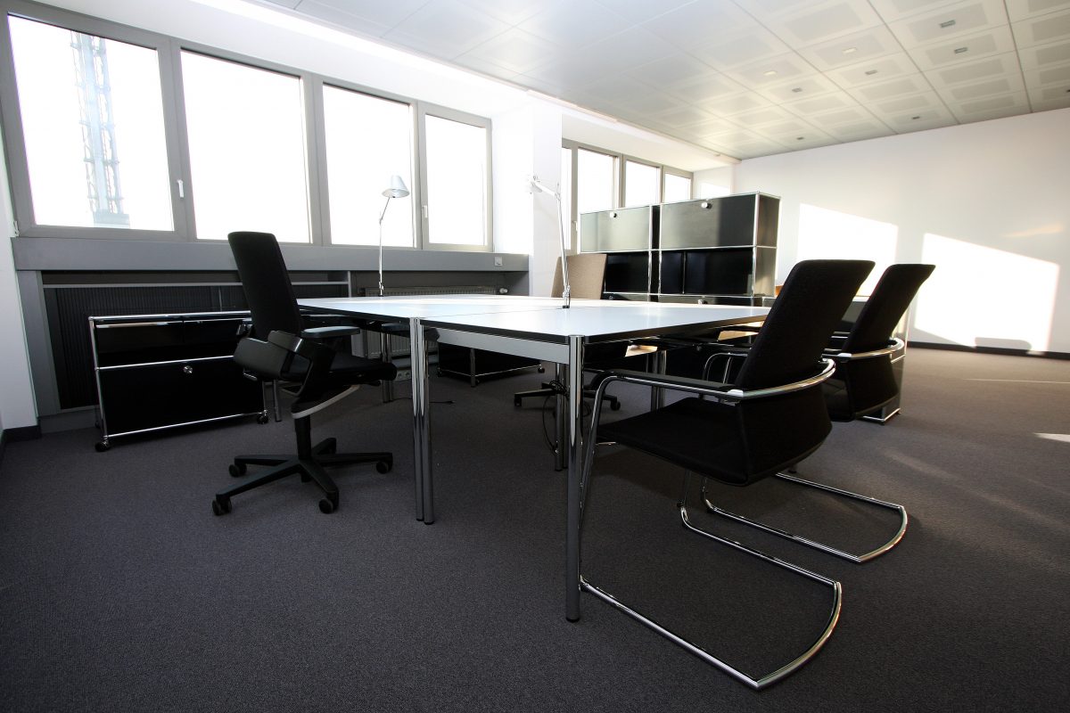 Modernes Büro mit großem Besprechungstisch, Designerstühlen und Tageslicht.