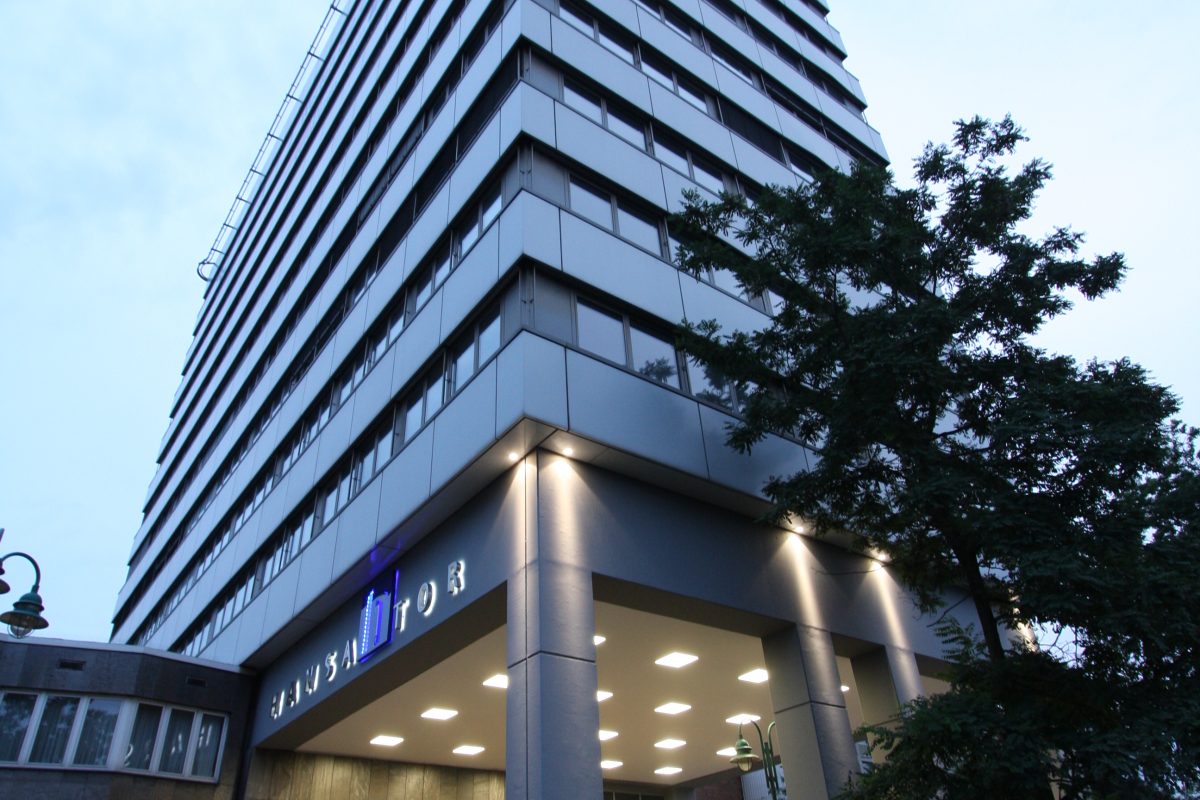 Modernes Verwaltungshochhaus bei Dämmerung mit beleuchtetem Eingang.