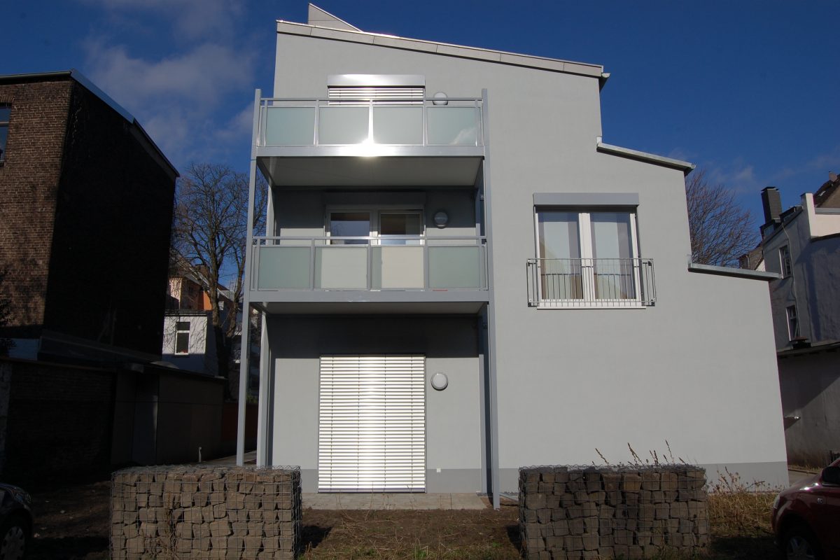 Modernes, dreigeschossiges Wohnhaus mit Balkonen und klarer Fassadengestaltung.