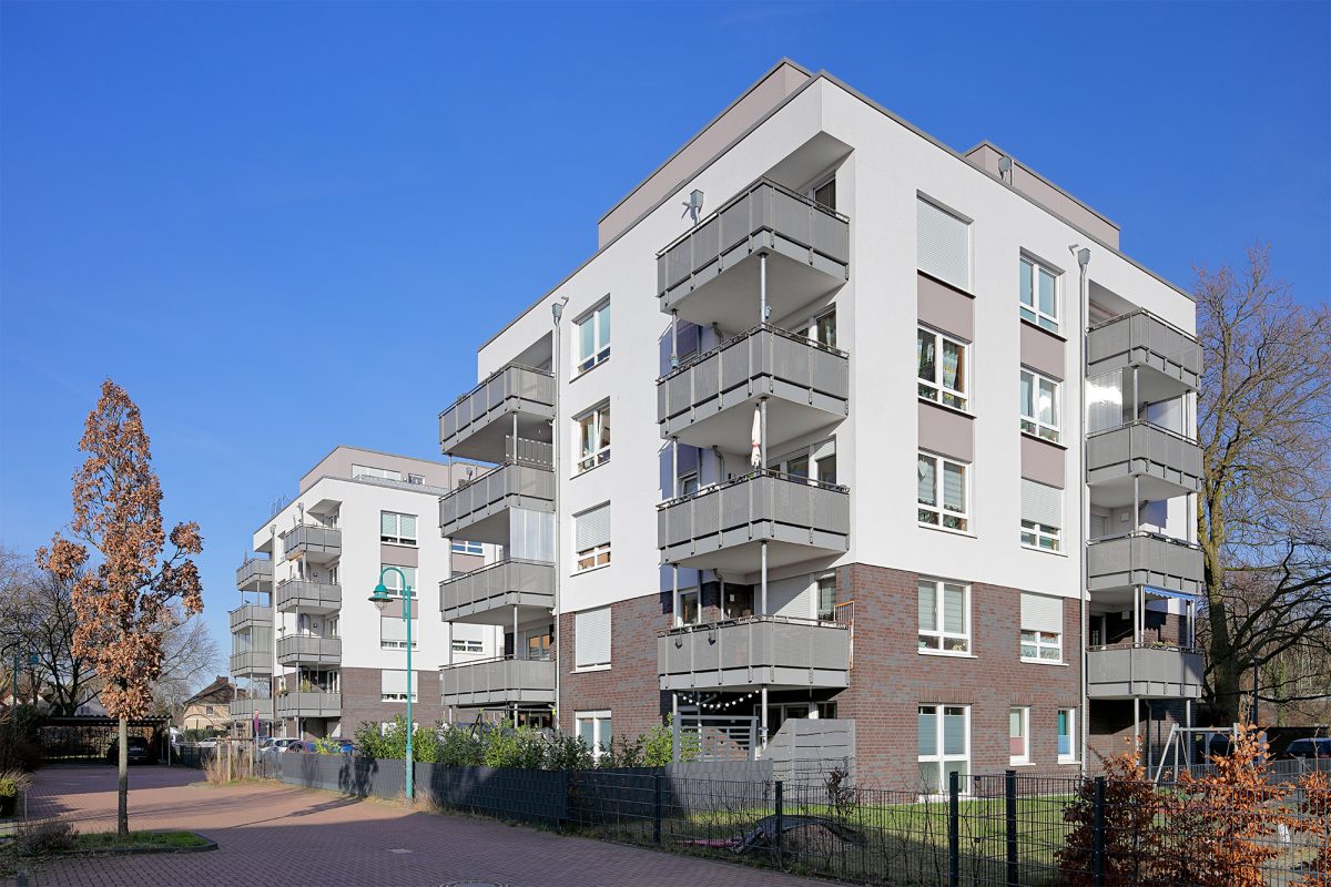 Zwei Mehrgeschossiges Wohnhäuser mit Balkonen und rotbraunem Klinkersockel.