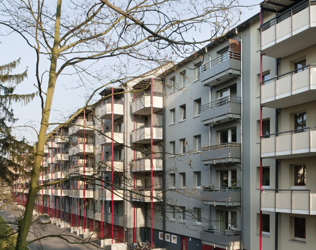 Hofseitige Balkonanlagen mit roten Rundstützen.