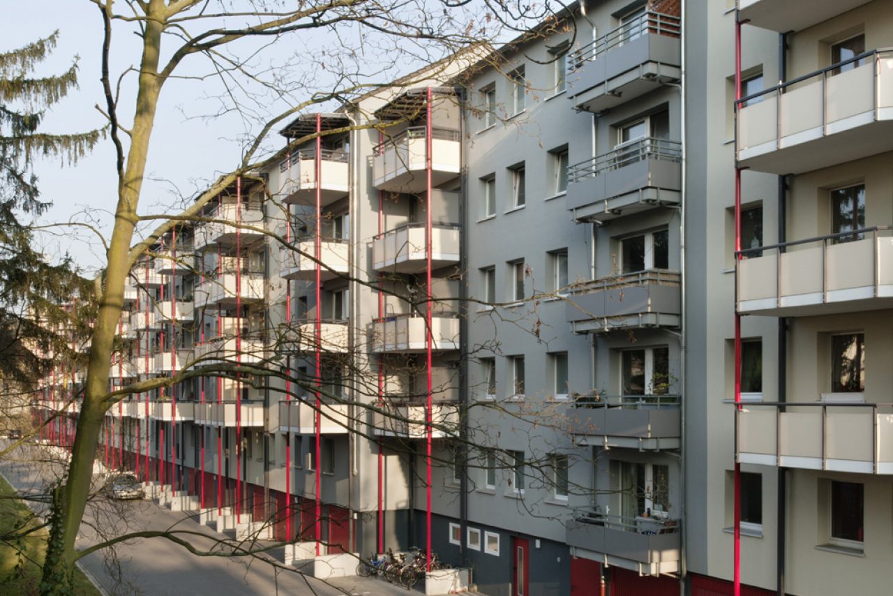 Hofseitige Balkonanlagen mit roten Rundstützen.