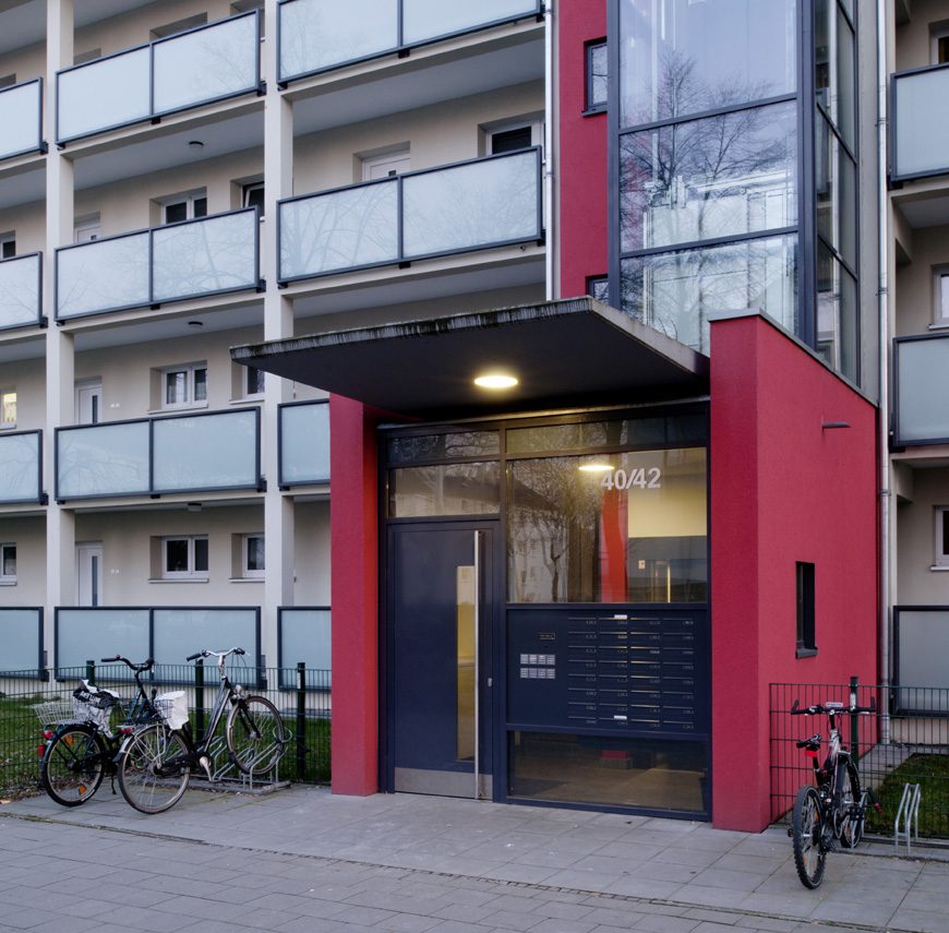 Hauseingang 40/42 mit rotem Vorbau, Glasfassade und Klingel- und Briefkastenanlage.