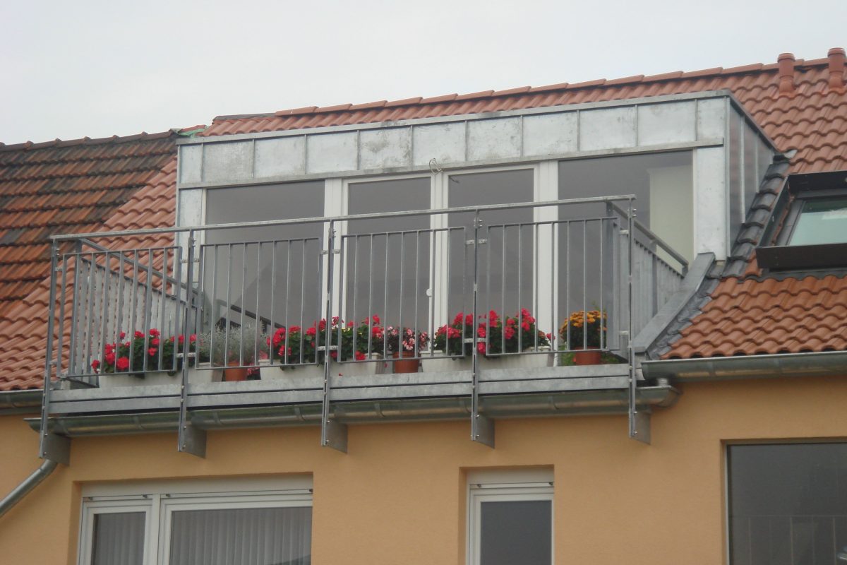 Dachgaube mit Zinkblechverkleidung und Balkon mit Blumenkästen.