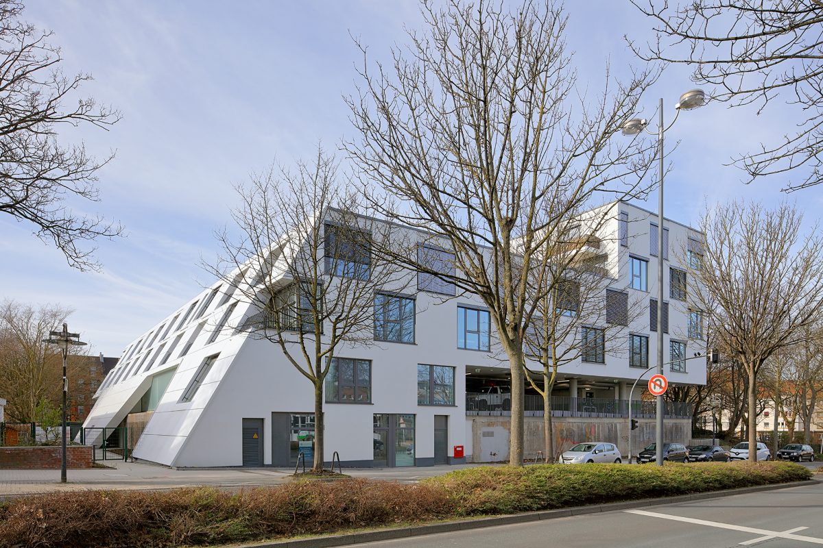 Straßenansicht eines modernen Wohnhauses mit schräger Fassade und integriertem Garagengeschoss