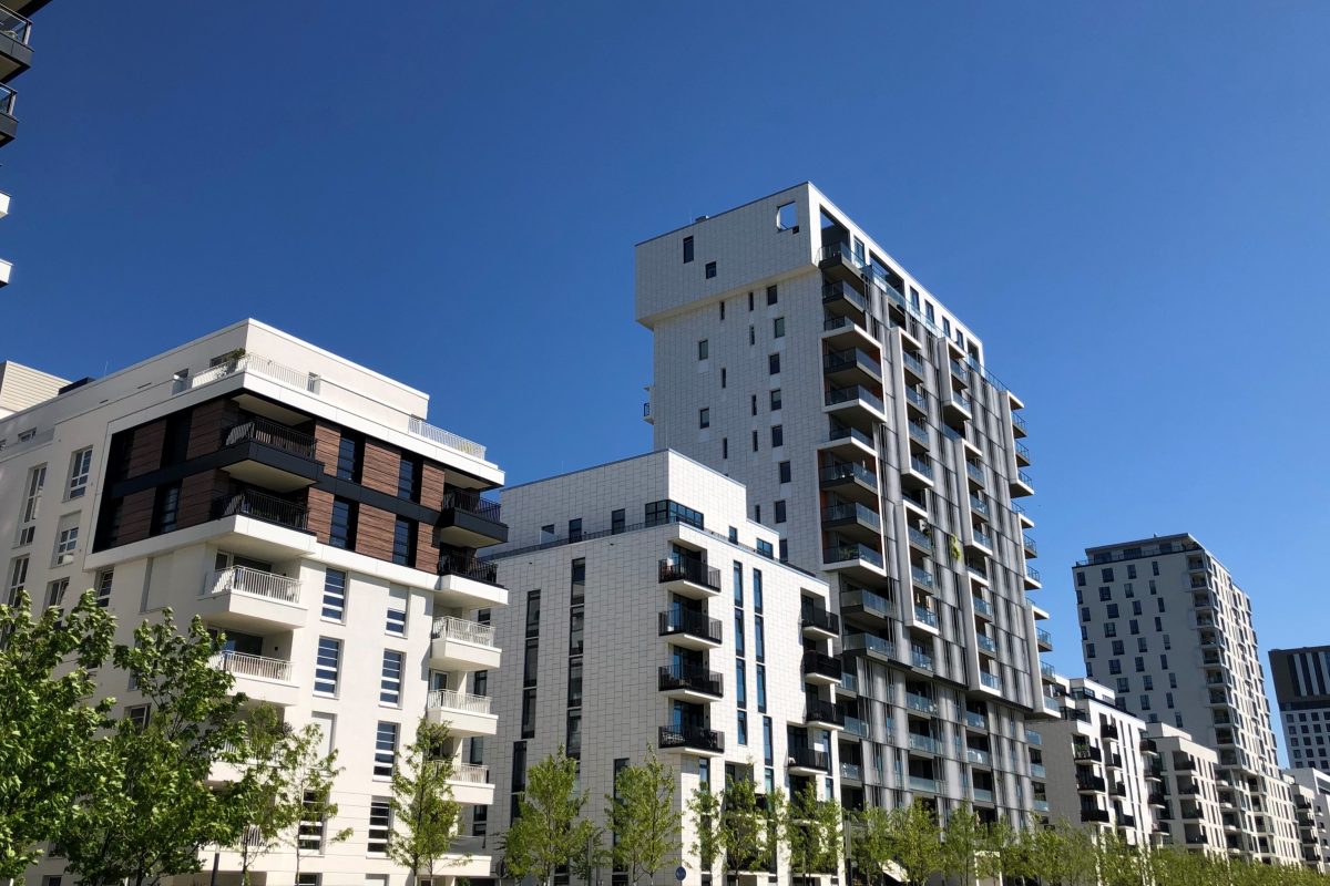 Moderne Wohngebäude mit Balkonen und klarer Architektur vor blauem Himmel.