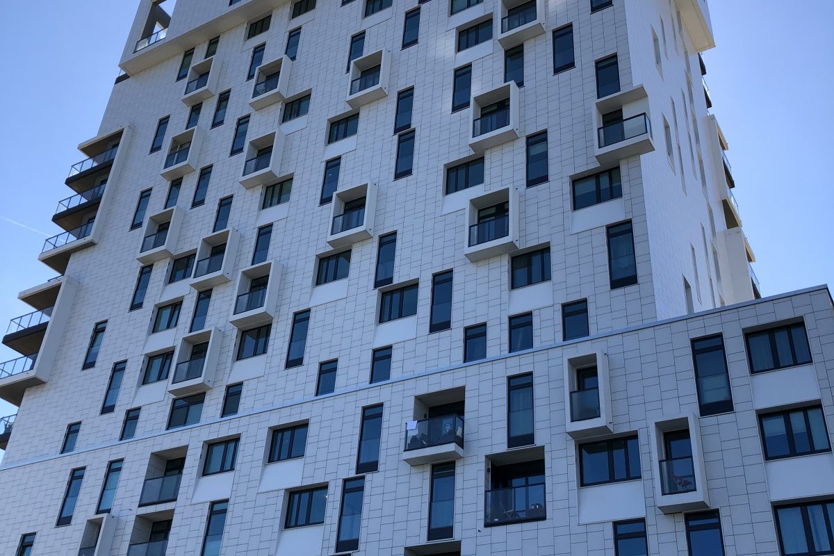 Hochhaus mit heller Kachelstruktur und versetzt angeordneten Fenstern.