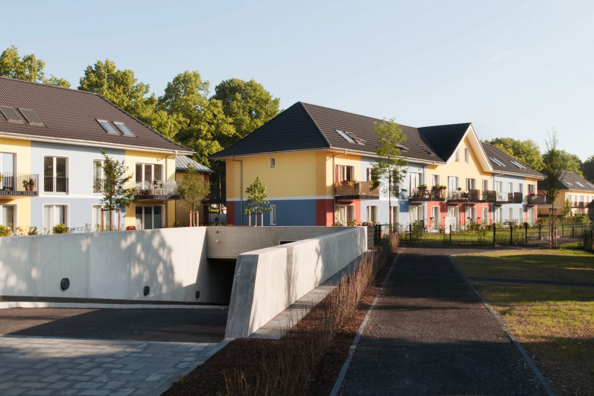 Moderne Wohnanlage mit Tiefgaragenzufahrt und farbiger Fassade.