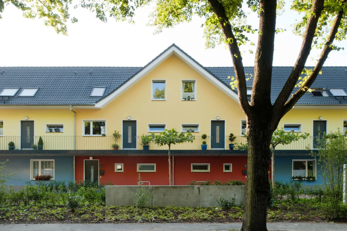 Zweigeschossiges Wohnhaus mit gelber Fassade und barrierefreiem Zugang.