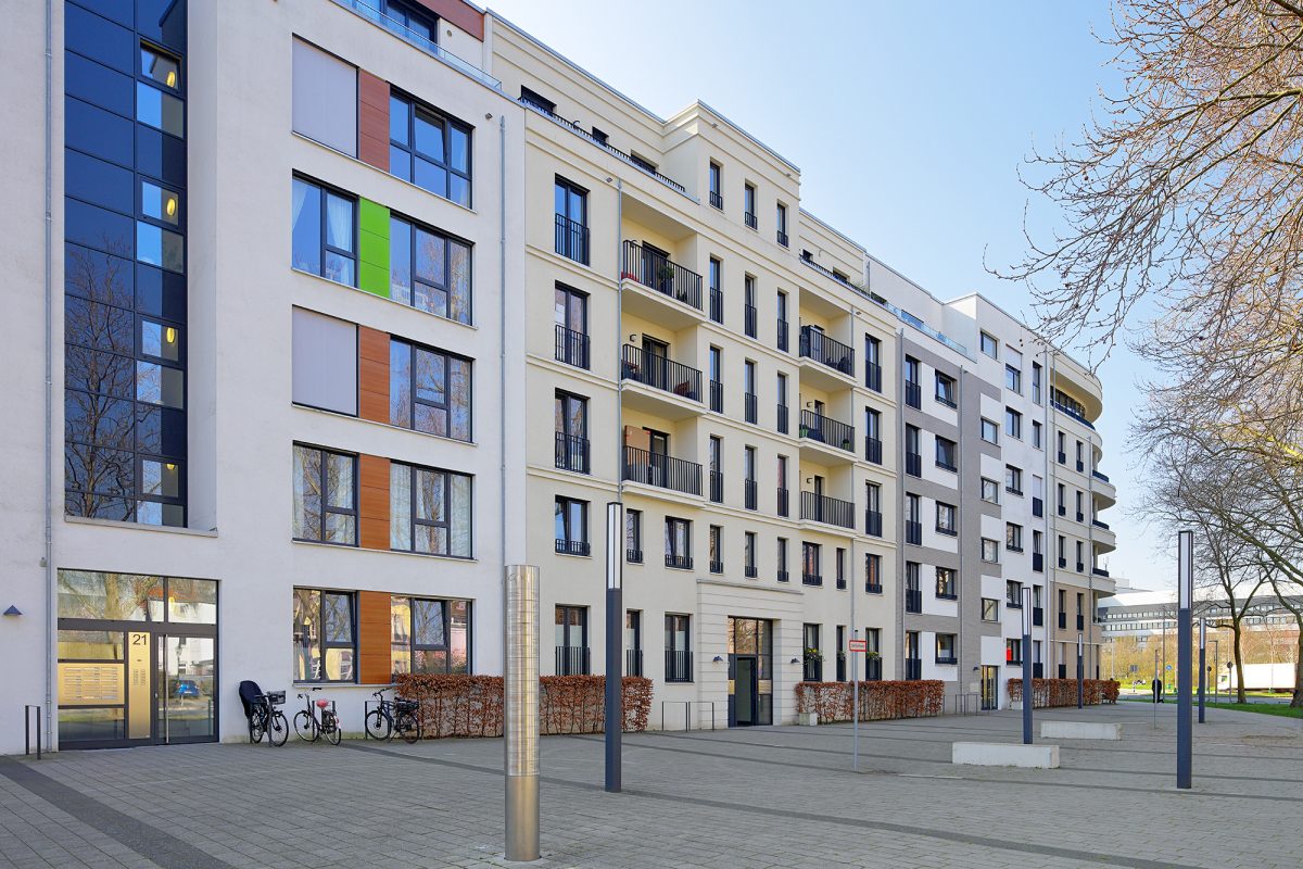 Modernes Mehrfamilienhaus mit Balkonen und farbigen Fassadenelementen.