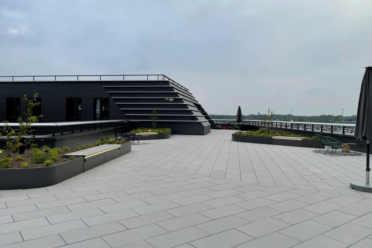 Weite Dachterrasse mit Pflanzinseln, Sitzplätzen und moderner Architektur.