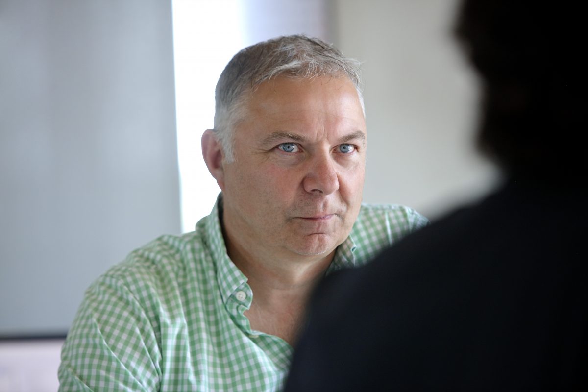 Mann mit grauen Haaren im karierten Hemd schaut konzentriert nach vorn.