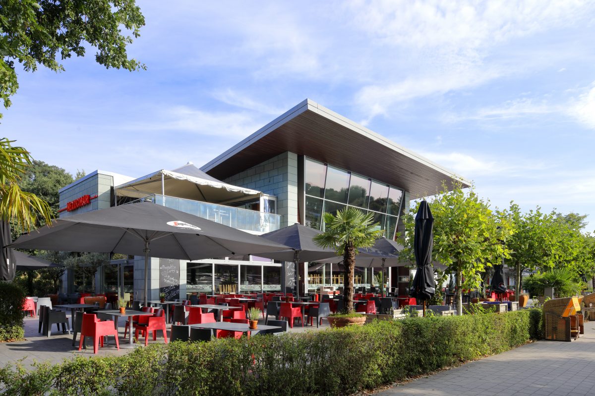 Modernes Restaurant mit großer Terrasse und roten Sitzmöbeln.