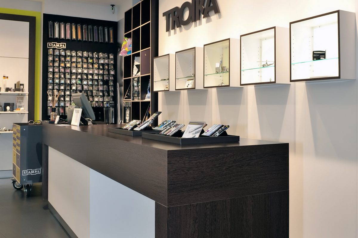 Moderner Verkaufsraum mit dunklem Tresen und beleuchteten Wandvitrinen