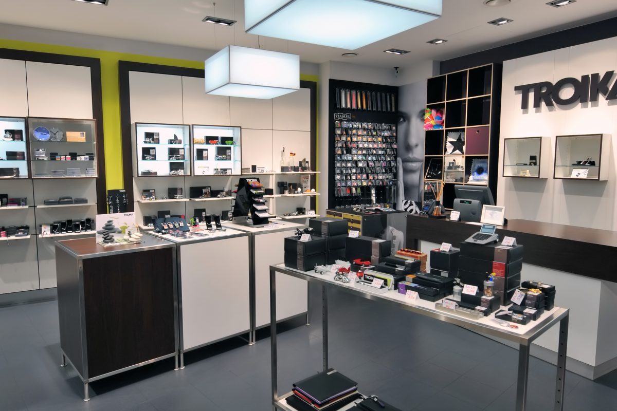 Modernes Geschäft mit beleuchteten Regalen und Verkaufstischen.