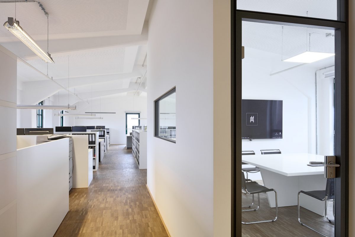 Büroflur mit Blick ins Großraumbüro und angrenzenden Besprechungsraum.