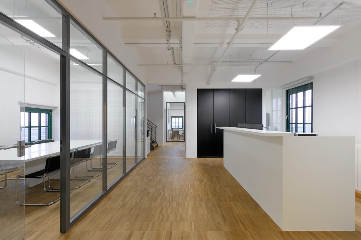 Heller Büroflur mit Empfangstresen und verglastem Besprechungsraum.