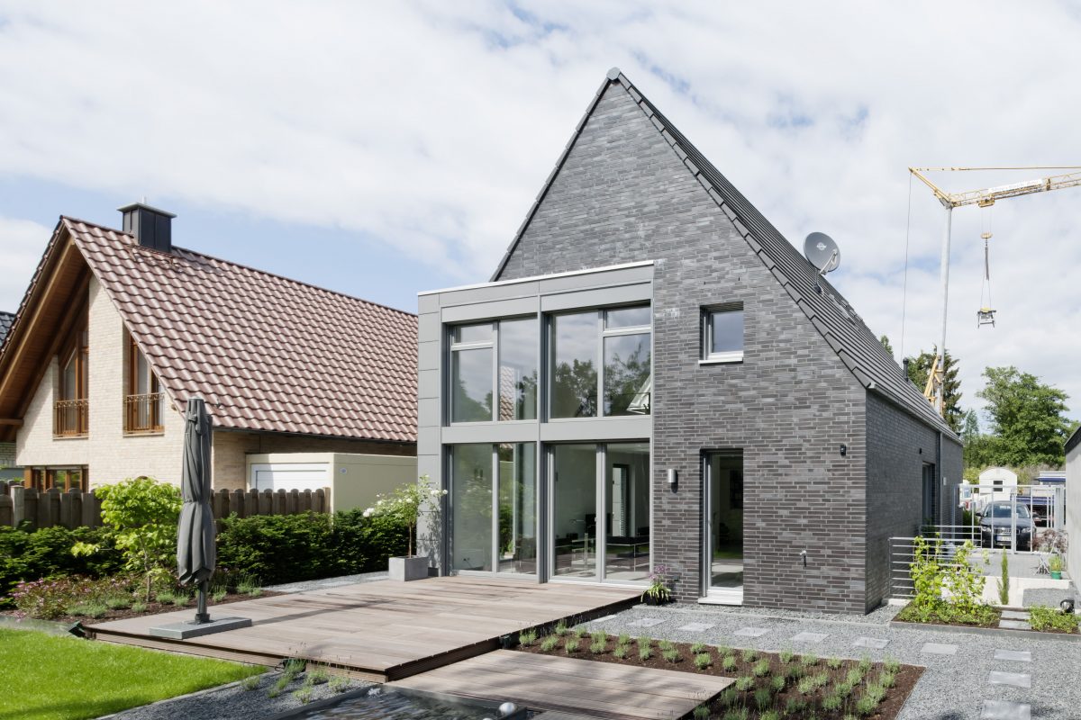 Haus mit Satteldach, moderner Klinkerfassade und großer Glasfront.