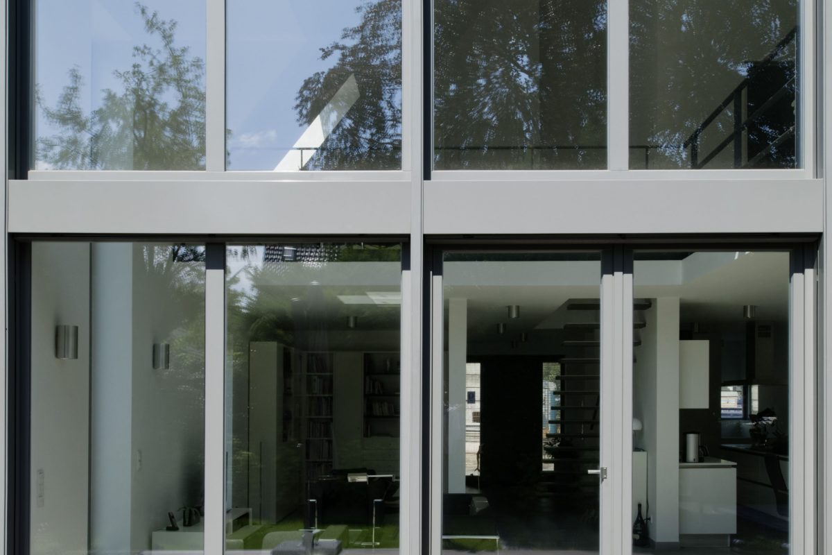 Modernes Haus mit großer Glasfront und Blick ins helle Wohnzimmer.