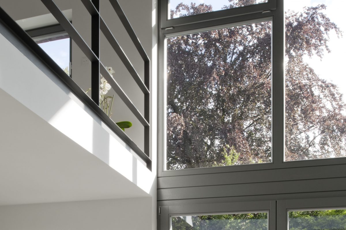 Großes Fenster mit Blick auf Baumkronen und Galeriegeländer.