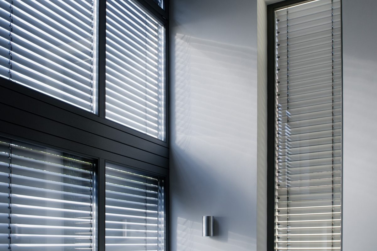 Große Fenster mit geschlossenen Jalousien und Schattenwurf.