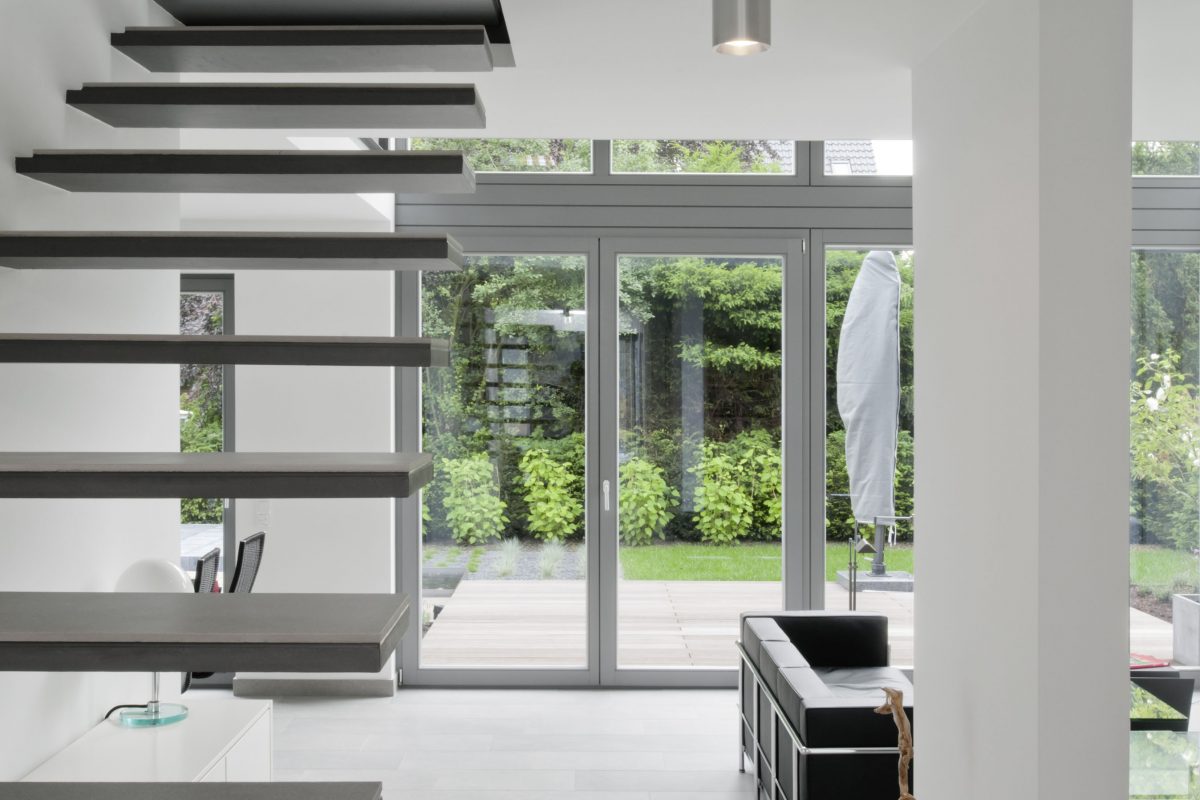 Offenes Wohnzimmer mit freier Treppe und Blick in den Garten.