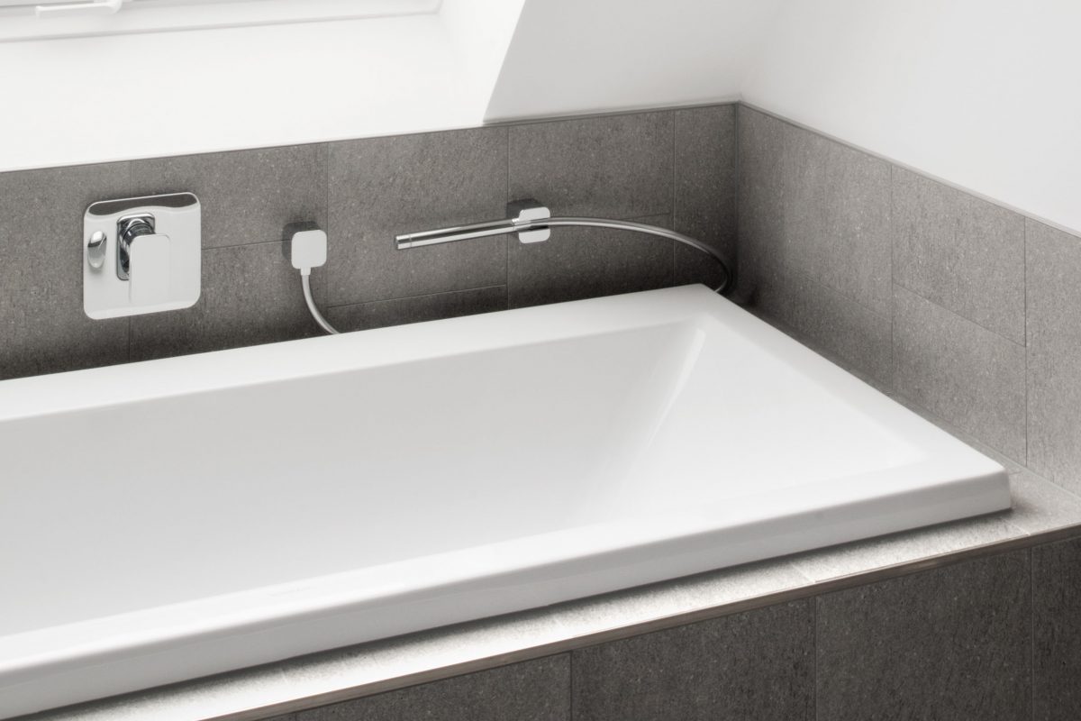 Badewanne mit grauen Fliesen und Dachfenster im modernen Badezimmer