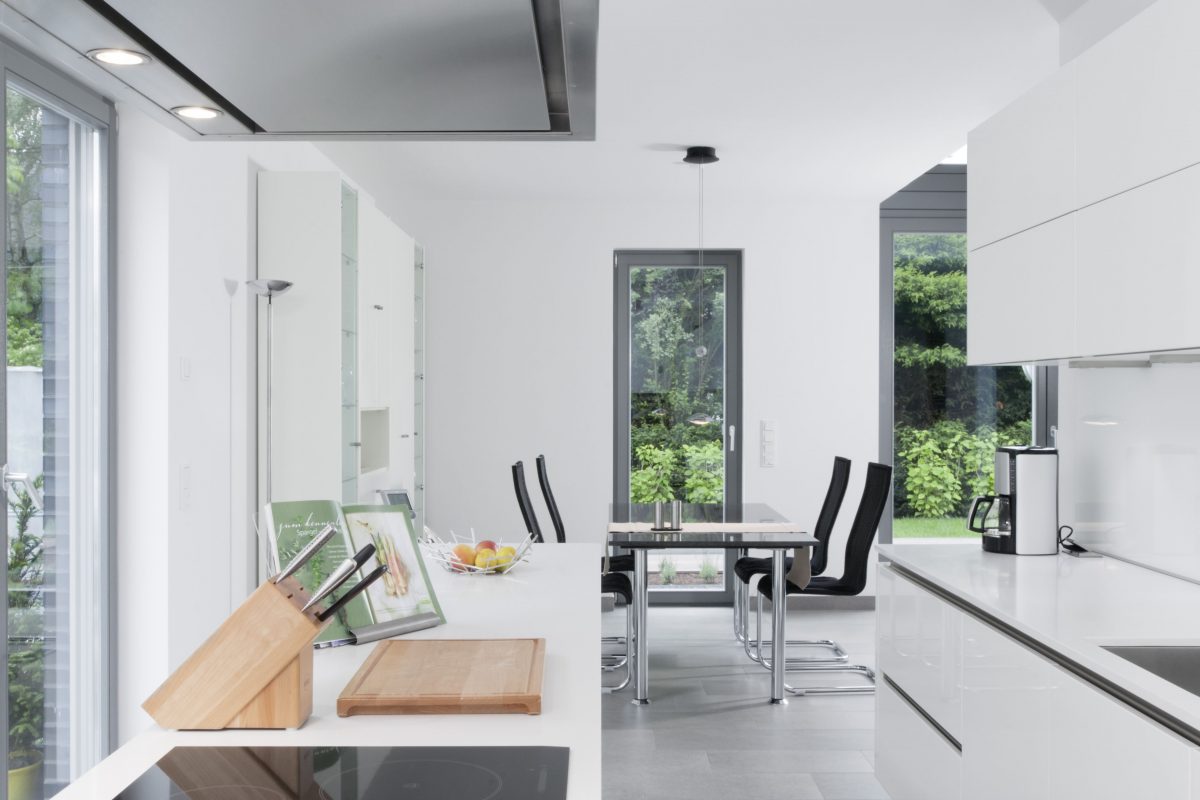 Moderne weiße Küche mit Kochinsel und Essbereich am Fenster