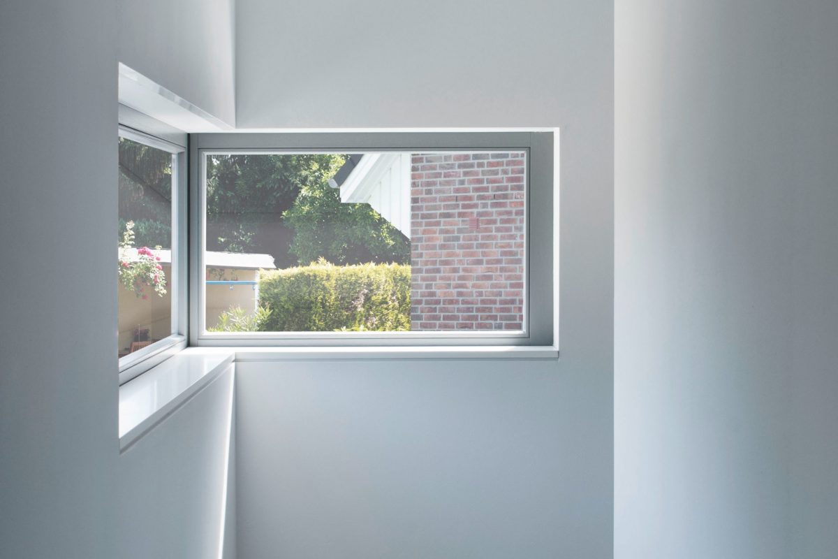 Helles Treppenhaus mit seitlichem Fenster und Blick ins Grüne